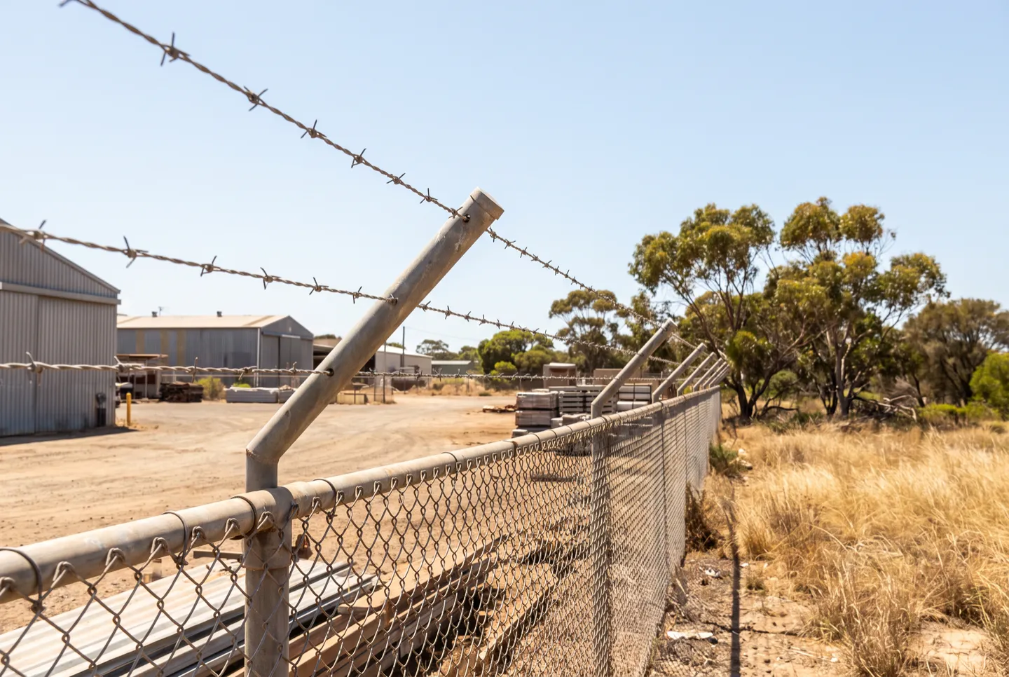 Barbed wire topping a chainwire industrial perimeter